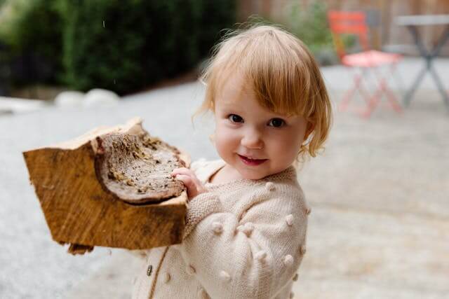 baby holding firewood