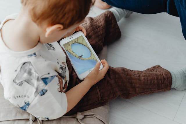 Toddler exposed to technology, using a phone.